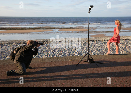 Photographer photographing a young female model on the promenade using off camera flash. Wales, UK. Stock Photo