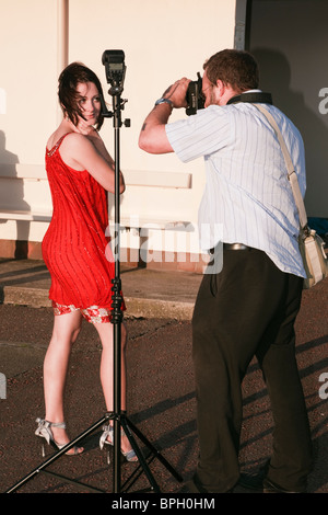 UK. Photographer photographing a young female model outside using off camera flash Stock Photo