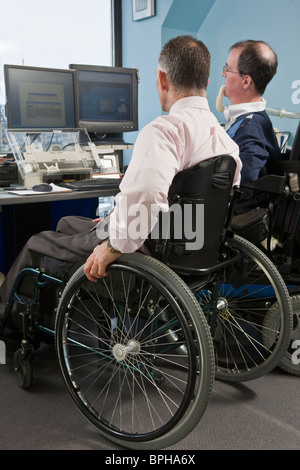 Two businessmen in a wheelchair working in an office Stock Photo
