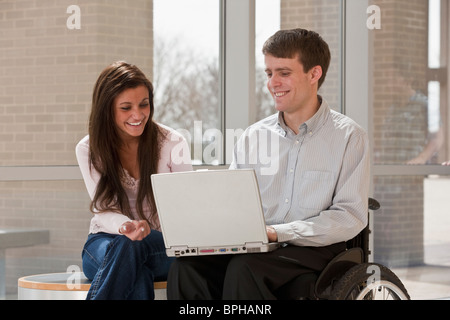 Teacher with spinal cord injury and a student using a laptop Stock Photo