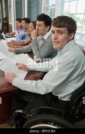 Businessman with spinal cord injury discussing with his colleague in a board room Stock Photo