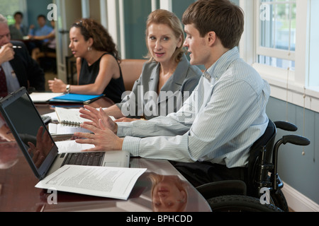 Businessman with spinal cord injury discussing with his colleague in a board room Stock Photo