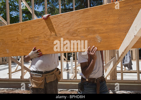 Carpenters lifting a laminated beam at a construction site