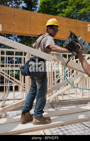 Carpenter preparing to nail a laminated beam in place Stock Photo