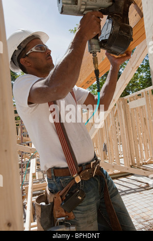 Carpenter using a nail gun at a construction site