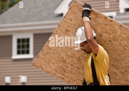 Carpenter carrying a particle board Stock Photo