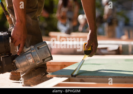 Carpenters holding a nail gun and measuring a board Stock Photo