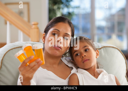 Hispanic woman sitting with her daughter and holding pill bottles Stock Photo