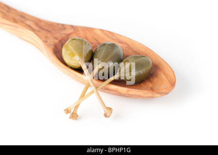 Three large capers in a wooden spoon isolated on a white background. Stock Photo