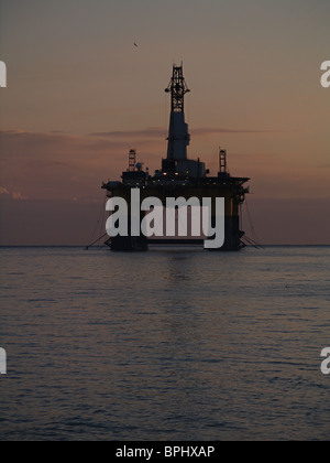 The Transocean Rather, a semi-submersible oil drilling rig, is silhouetted against the dawn, Cromarty Firth, Scotland Stock Photo