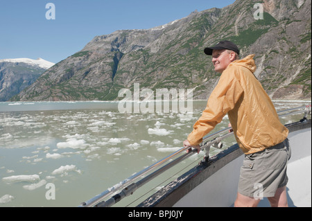 Man enjoys spectacular scenery of mountains and ice bergs whilst on Alaska cruise in Tracy Arm Fjord. Stock Photo