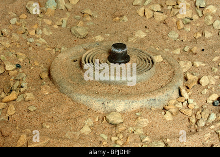 An IED mine exposed in the desert sand Stock Photo