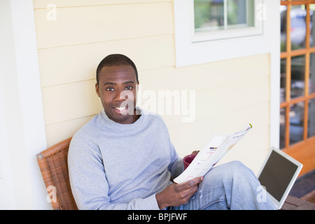 Black man on porch reading magazine Stock Photo
