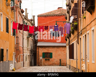 backyard at Venice, red and purple clothes drying on clothes-line, woman hanging a shirt from her window Stock Photo