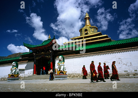 Local monks passing Gong Tang pagoda at Labrang Lamma Buddhist monastery (Yellow Hat) in the town of Xiahe in Gansu. Stock Photo