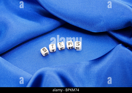 Royal blue satin background with rich folds and wrinkles for texture is the word stews in cube lettering in this series. Stock Photo