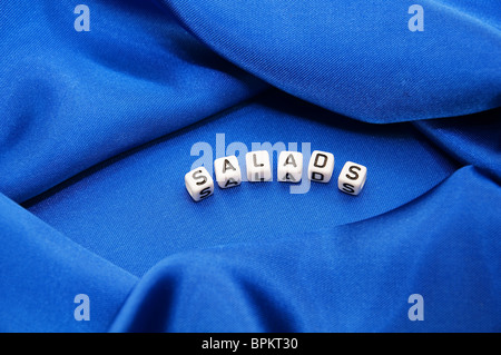 Royal blue satin background with rich folds and wrinkles for texture is the word salads in black and white  lettering series Stock Photo