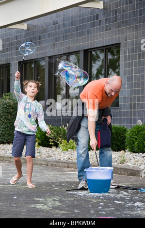 A father and daughter enjoy making giant soap bubbles during the Sand in the City celebration in Olympia, Washington. Stock Photo