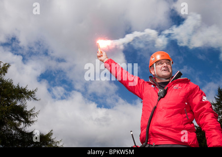 A member of Langdale/Ambleside Mountain Rescue Team uses a flare to attract an incoming Sea King helicopter Stock Photo
