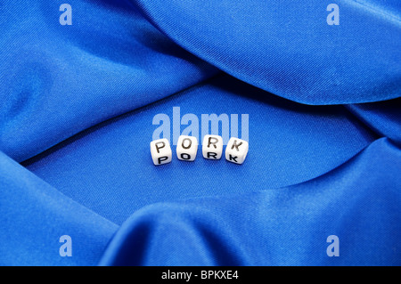 Royal blue satin background with rich folds and wrinkles for texture is the word pork in black and white cube lettering series Stock Photo