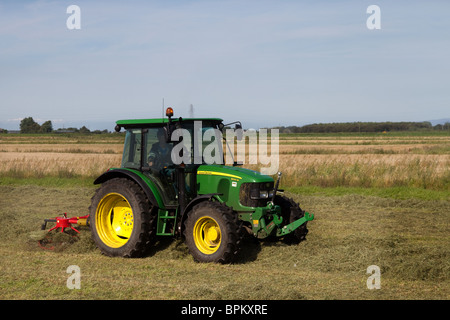 John Deere Tractor rotating hay at Mere Brow, Hesketh Bank, Southport, Lancashire, uk Stock Photo