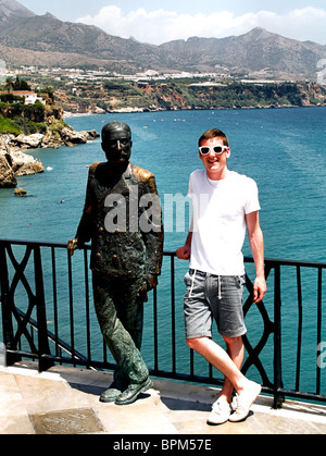 A young man stands next to the statue of King Alfonso XII on the  Balcón de Europa , in Nerja, Andalucia, Spain Stock Photo