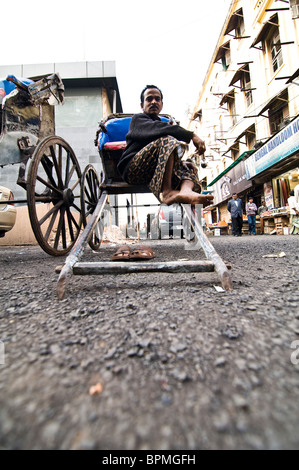 A hand pulled rickshaw puller in the old and narrow streets of Kolkata. Stock Photo