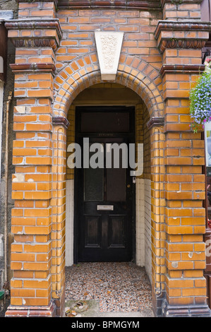 Victorian wood paneled and glass black painted front door with glazed brick porch in Llandrindod Wells Powys Mid Wales UK Stock Photo