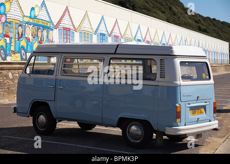 VW automatic campervan with colourful painted beach huts on building behind at promenade between Bournemouth and Boscombe, Dorset UK Stock Photo