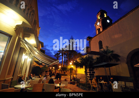 People in street cafes at the church Nuestra Senora in the evening, Puerto de la Cruz, Tenerife, Canary Isles, Spain, Europe Stock Photo
