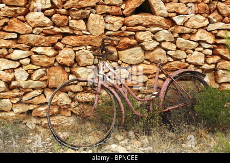 aged weathered bicycle vintage masonry stone wall in Formentera Balearic islands Stock Photo