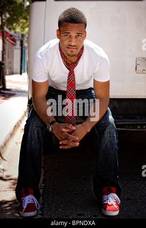 Young model black male wearing jeans and white tee shirt with red sneakers Stock Photo