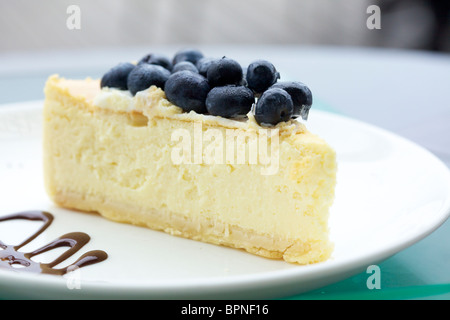 A slice of baked cheesecake with fresh blueberries on top Stock Photo