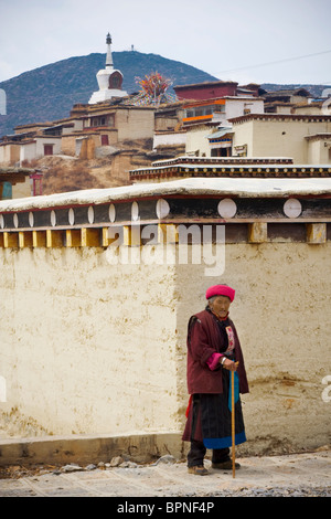 An old lady dressed in traditional minority dress walks near songzanlin tibetan monastery,shangri-la (Zhongdian) Yunnan, China. Stock Photo