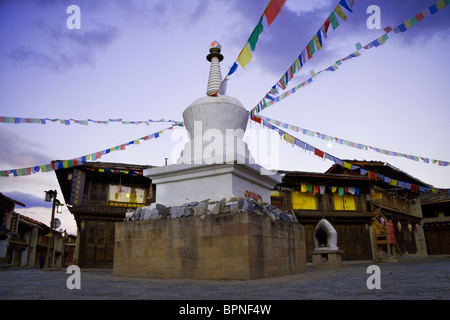 Prayer flags fly from a tibetan chorten/pagoda in a small square in shangri-la (Zhongdian) Yunnan, China. Stock Photo