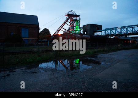 A colliery pit head and winding gear illuminated by green light