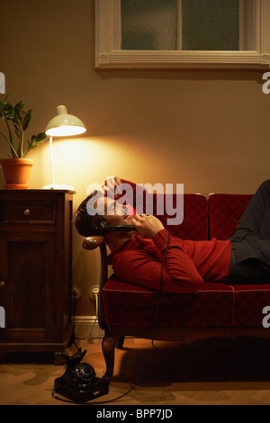 Man lying on couch phoning Stock Photo