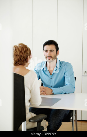 Man sitting opposite woman in office Stock Photo