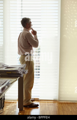 Man looking out of office window Stock Photo