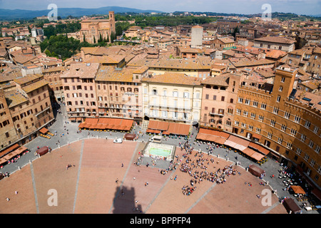 ITALY Tuscany Siena Piazza del Campo with surrounding buildings and rooftops and countryside beyond and square busy with people Stock Photo