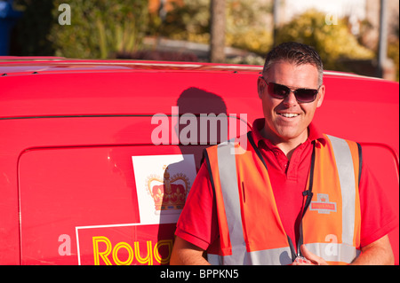 A postman standing next to his Royal mail van in the Uk Stock Photo