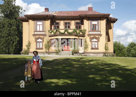Swedish woman and girl in national folk dress in front of countryside residential building Stock Photo