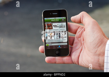 The iPhone 4 in the palm of a hand of a man, showing Spotify Stock Photo