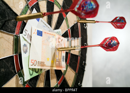 Darts pinning banknotes to a dartboard Stock Photo