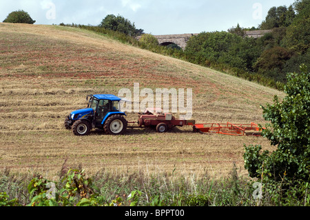Farmer bailing the hay crop using older style equipment in South Devon Stock Photo