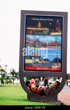 Young children sleeping under tourism sign in downtown Phnom Penh- Cambodia. Stock Photo