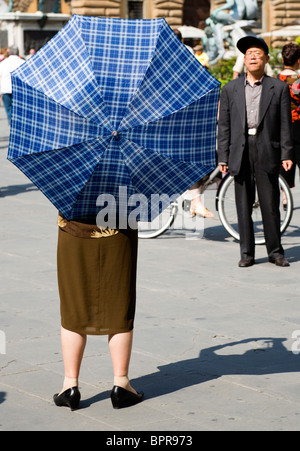 ITALY Tuscany Florence Elderly senior Asian tourist couple in Piazza della Signoria with the woman under an umbrella for shade Stock Photo