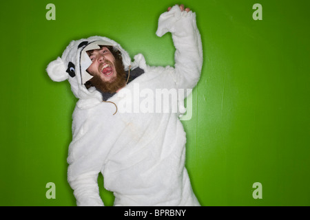 Young man with beard in a polar bear suit growling on green background. Stock Photo