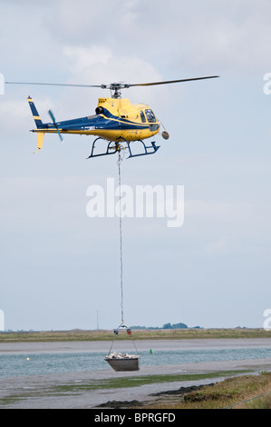 Helicopter carrying out emergency repairs to the sea wall on the River Roach Essex Stock Photo