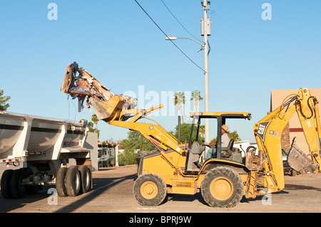 A backhoe is being used to remove debris from the demolition of  an old commercial building. Stock Photo
